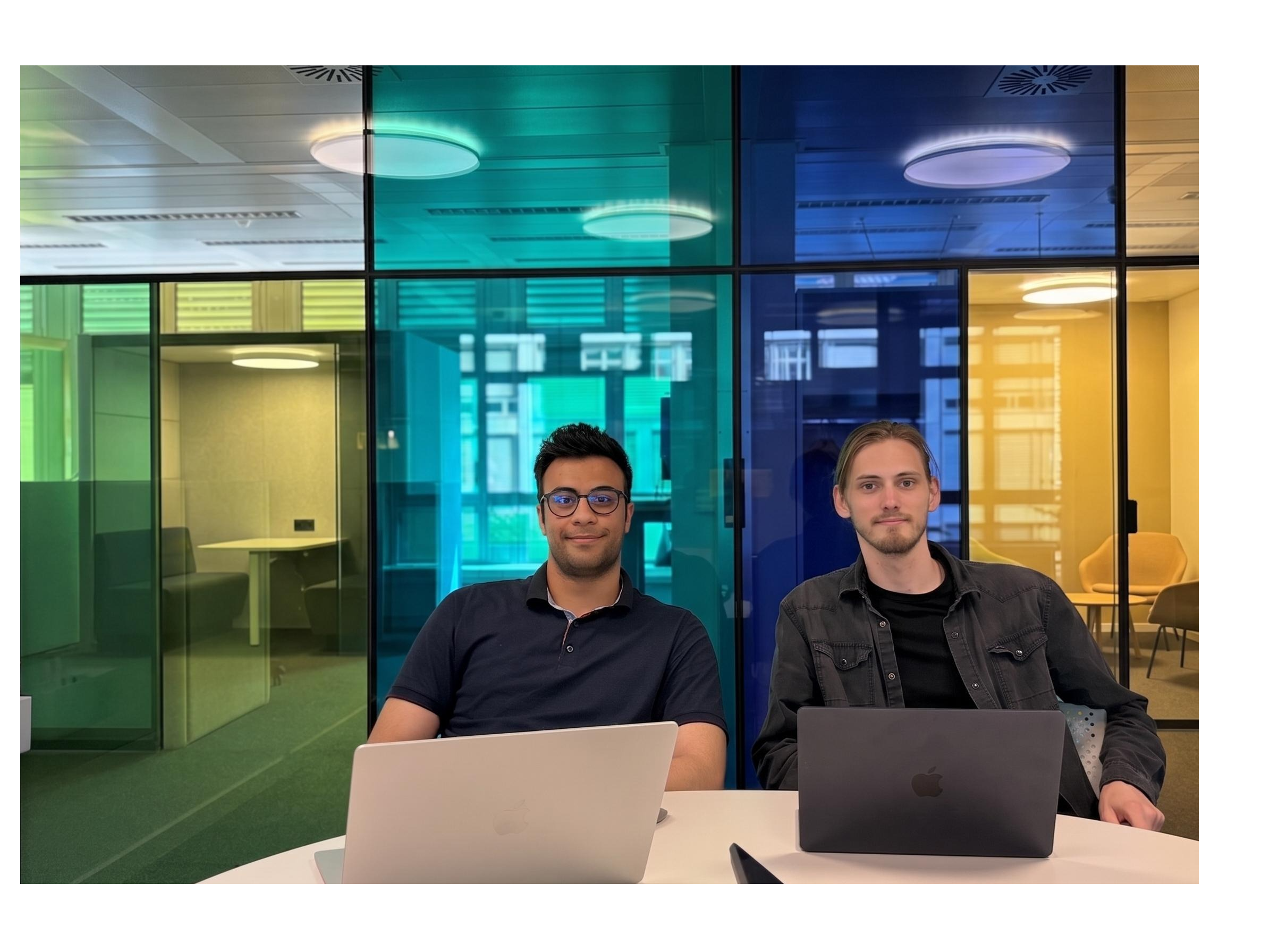deux entrepreneurs tech professionnels debout dans un bureau moderne et minimaliste avec des parois vitrées, éclairage cinématographique doux, regard concentré